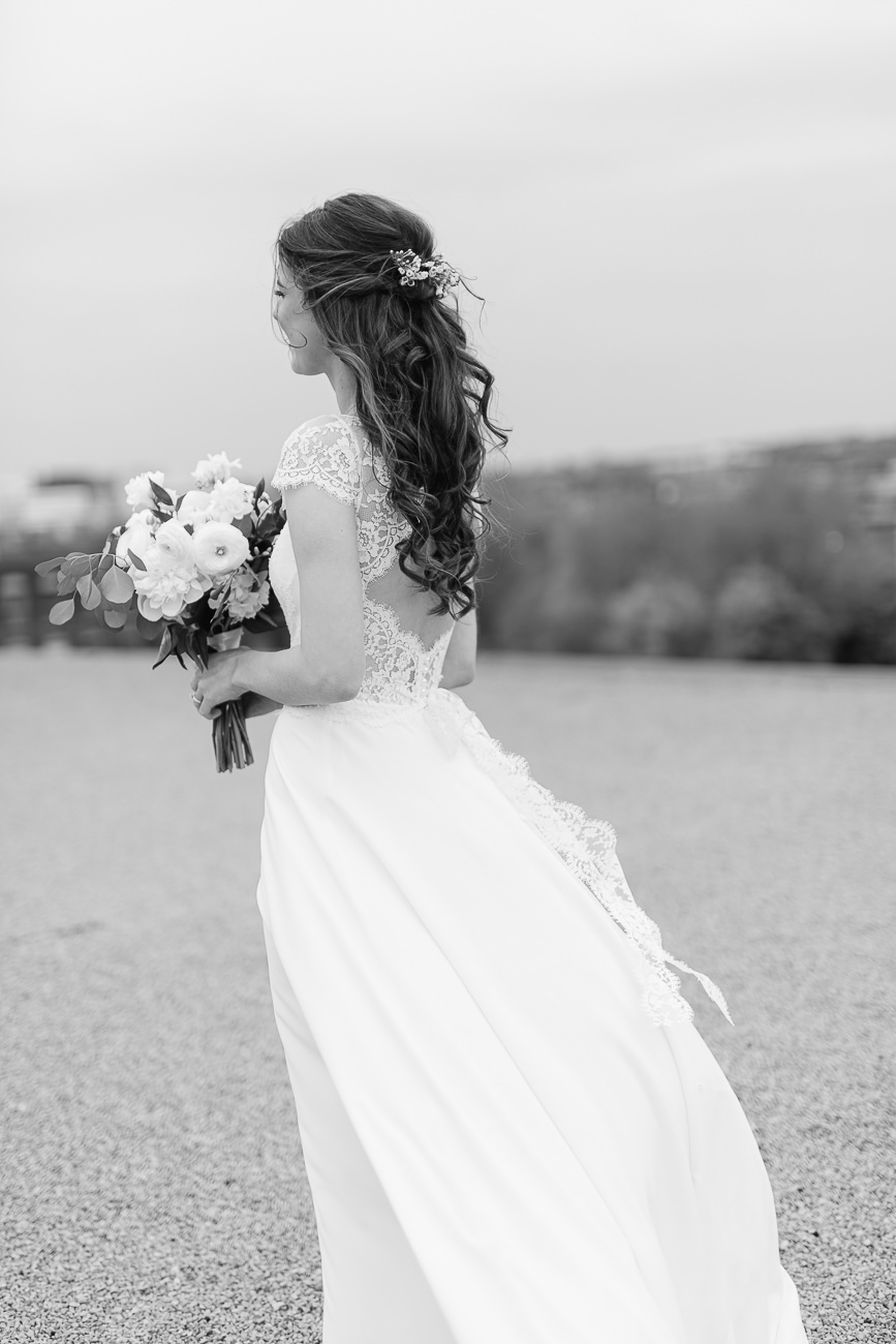 La mariée de dos dans sa jolie robe de mariage tient son bouquet de fleurs.