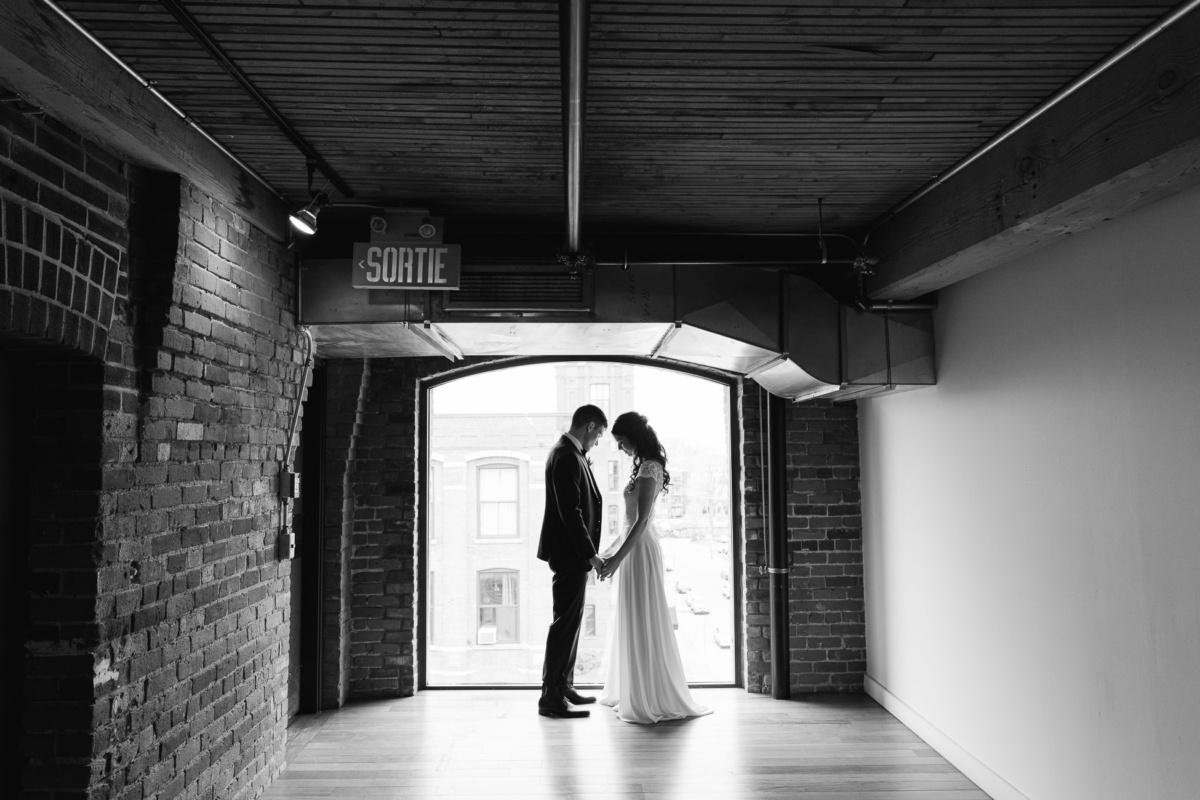 Les mariés devant une fenêtre. Mariage aux Entrepôts Dominion, Montréal.