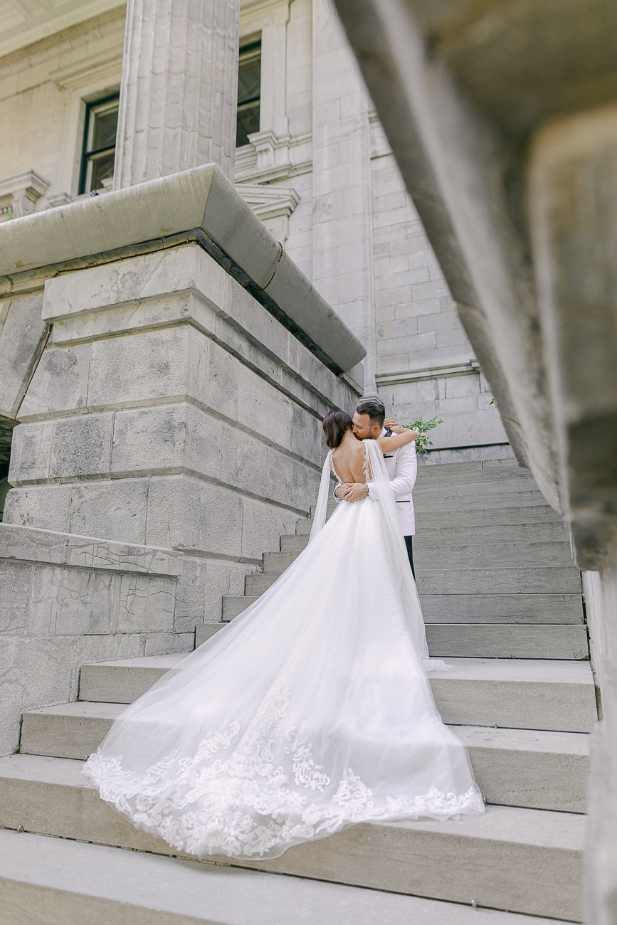 Portrait d'un couple de marié au Vieux Montréal. La mariée est vêtue d'une robe avec une très longue traine.
