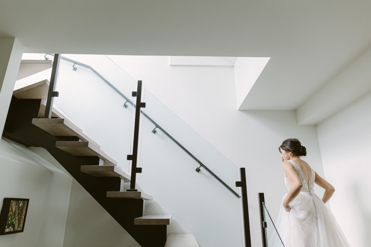La mariée vêtue de sa belle robe de mariage monte les escaliers.