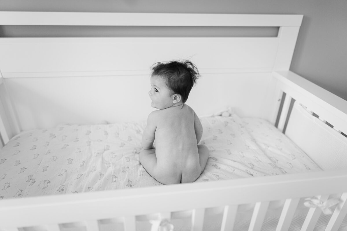 Un bébé fesses nues dans son petit lit. Séance photo en famille à la maison.