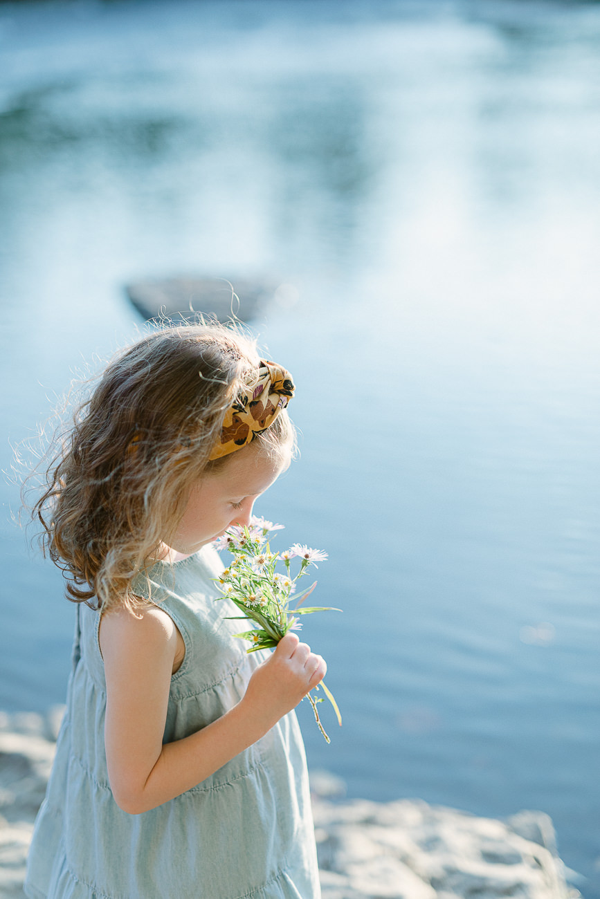 Une jeune fille qui tient un petit bouquet de fleurs près d'une rivière.