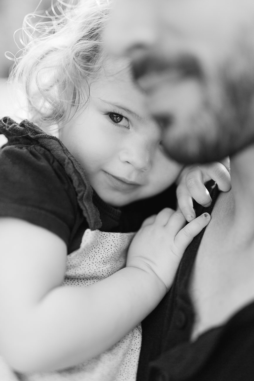 Portrait d'une petite fille dans les bras de son papa, séance en famille.